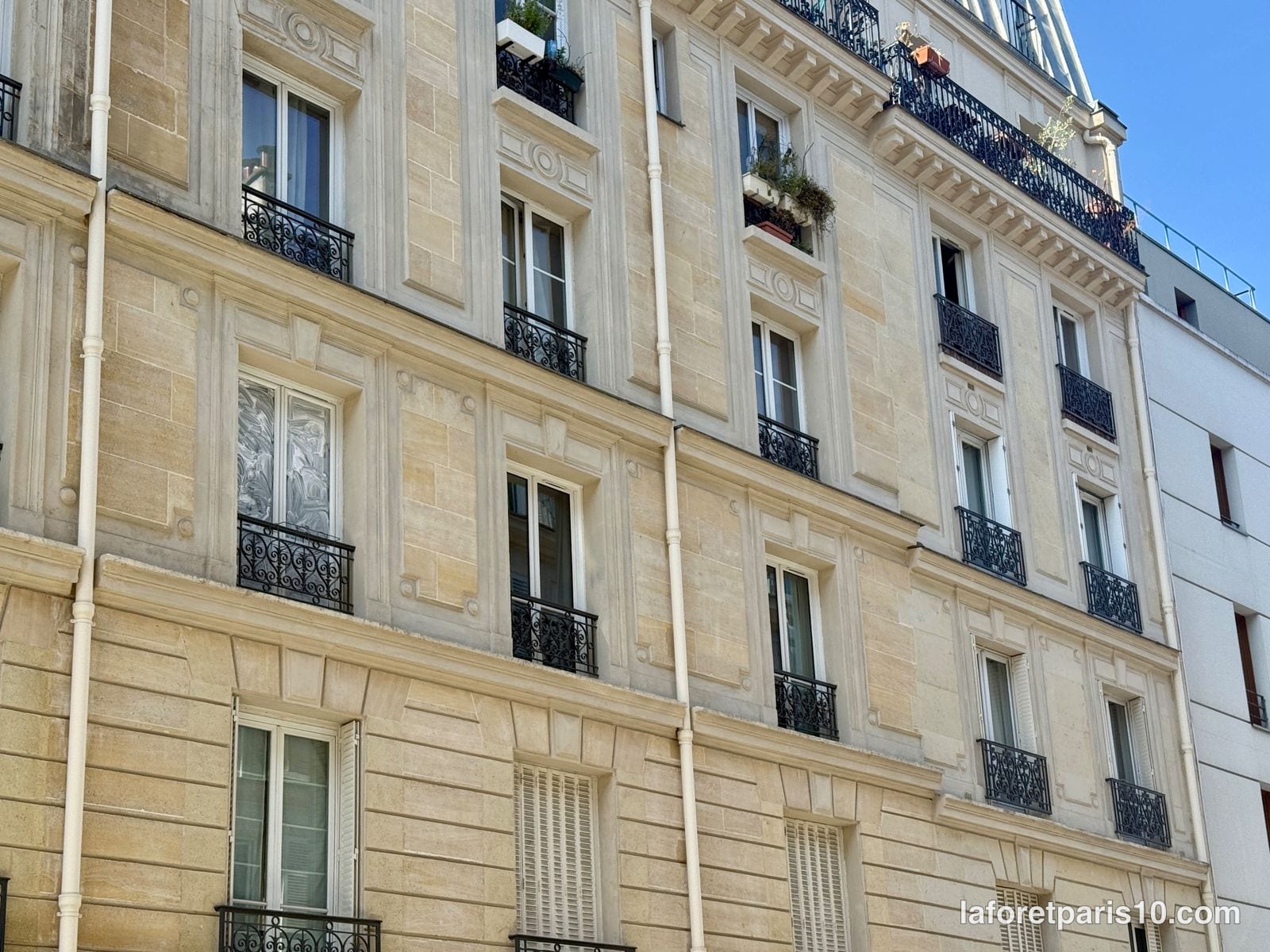 Détail de la façade du 23 rue Chaudron à Paris 10e : médaillons sculptés, refends de pierre et balconnets en fer forgé