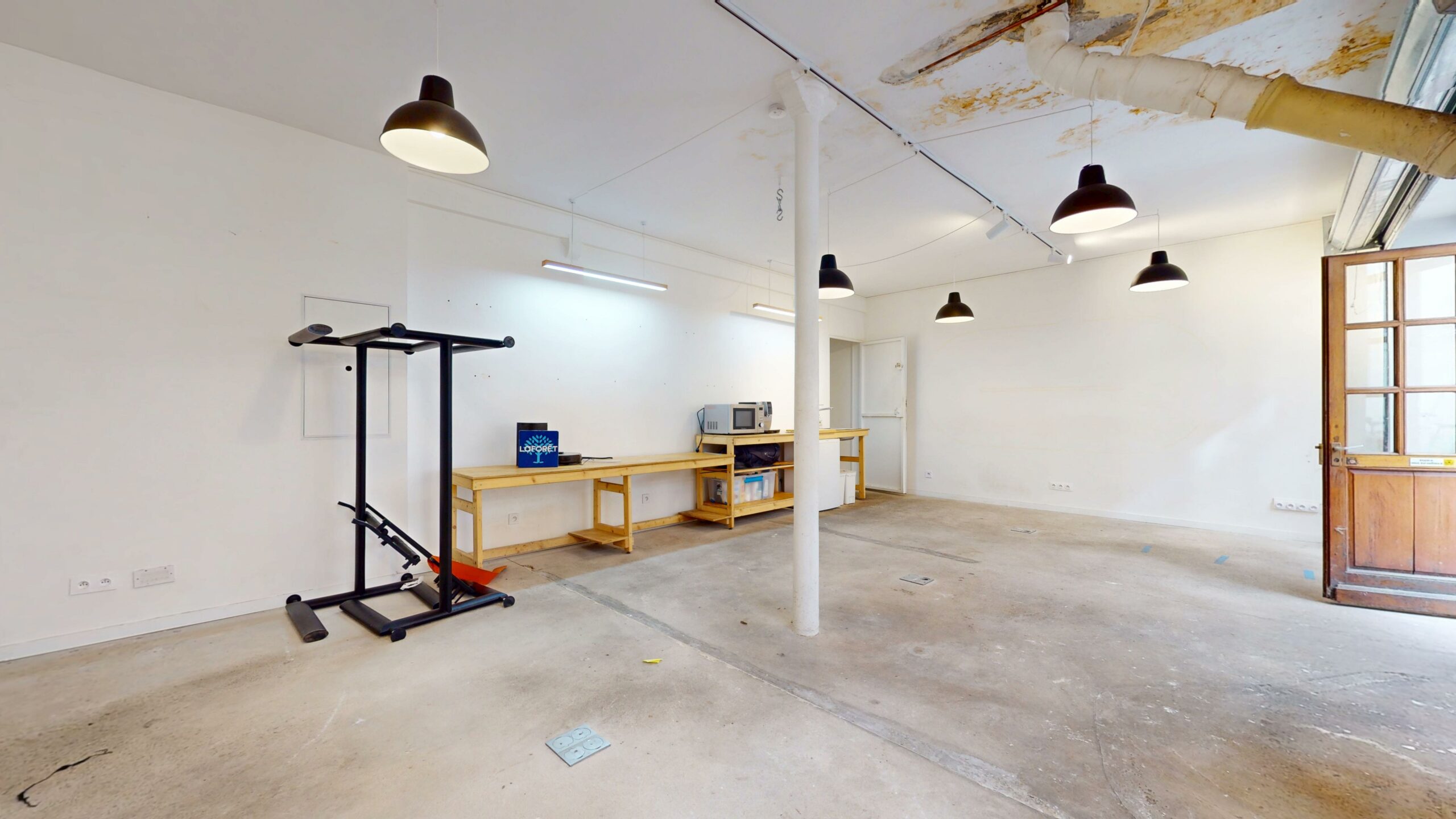 Volume dégagé avec poteau central et sol béton, plafond marqué par le dégât des eaux traité — local commercial 44 m² à louer, rue du Faubourg Saint-Martin, Paris 10e