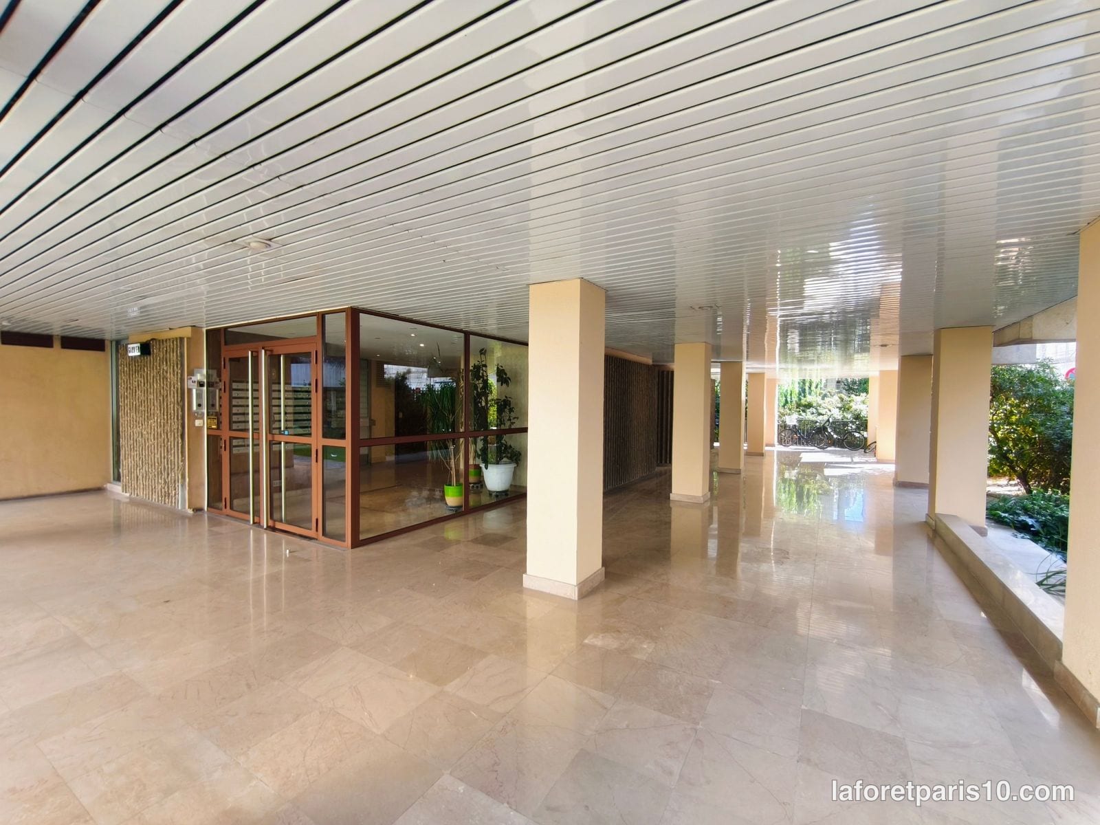 Hall d'entrée traversant de la résidence du 18 rue Euryale-Dehaynin, Paris 19e, ouvert sur le jardin