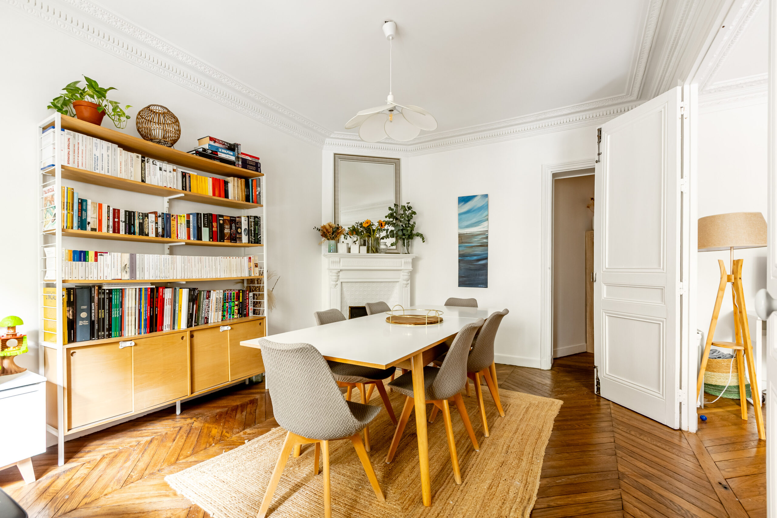Salle à manger d'un appartement 4 pièces 100,5 m², rue Caulaincourt, Paris 18e : bibliothèque, cheminée à miroir, moulures et parquet en point de Hongrie