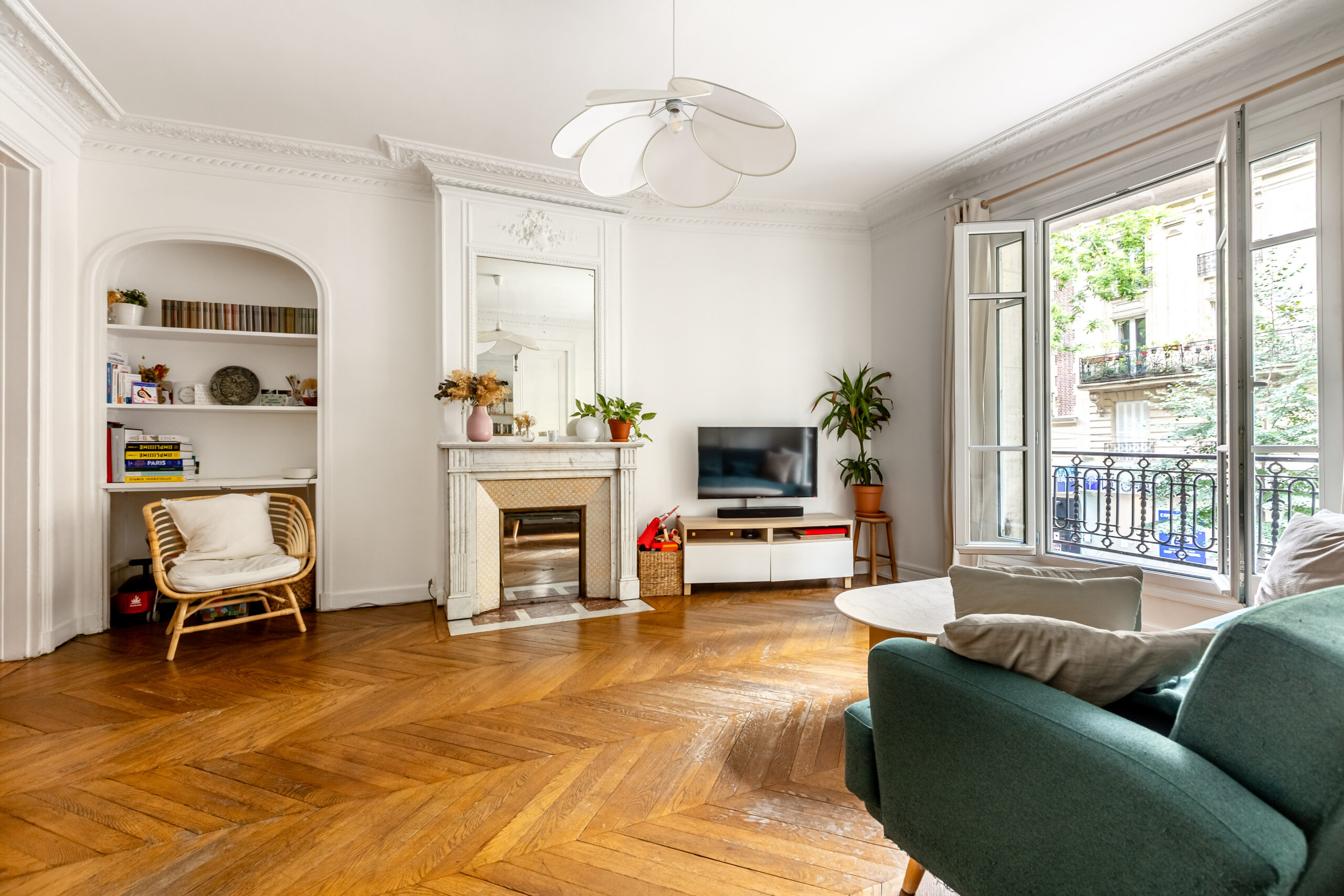 Séjour d'un appartement 4 pièces 100,5 m², rue Caulaincourt, Paris 18e : cheminée de marbre surmontée d'un trumeau, bibliothèque en niche voûtée et porte-fenêtre sur balcon