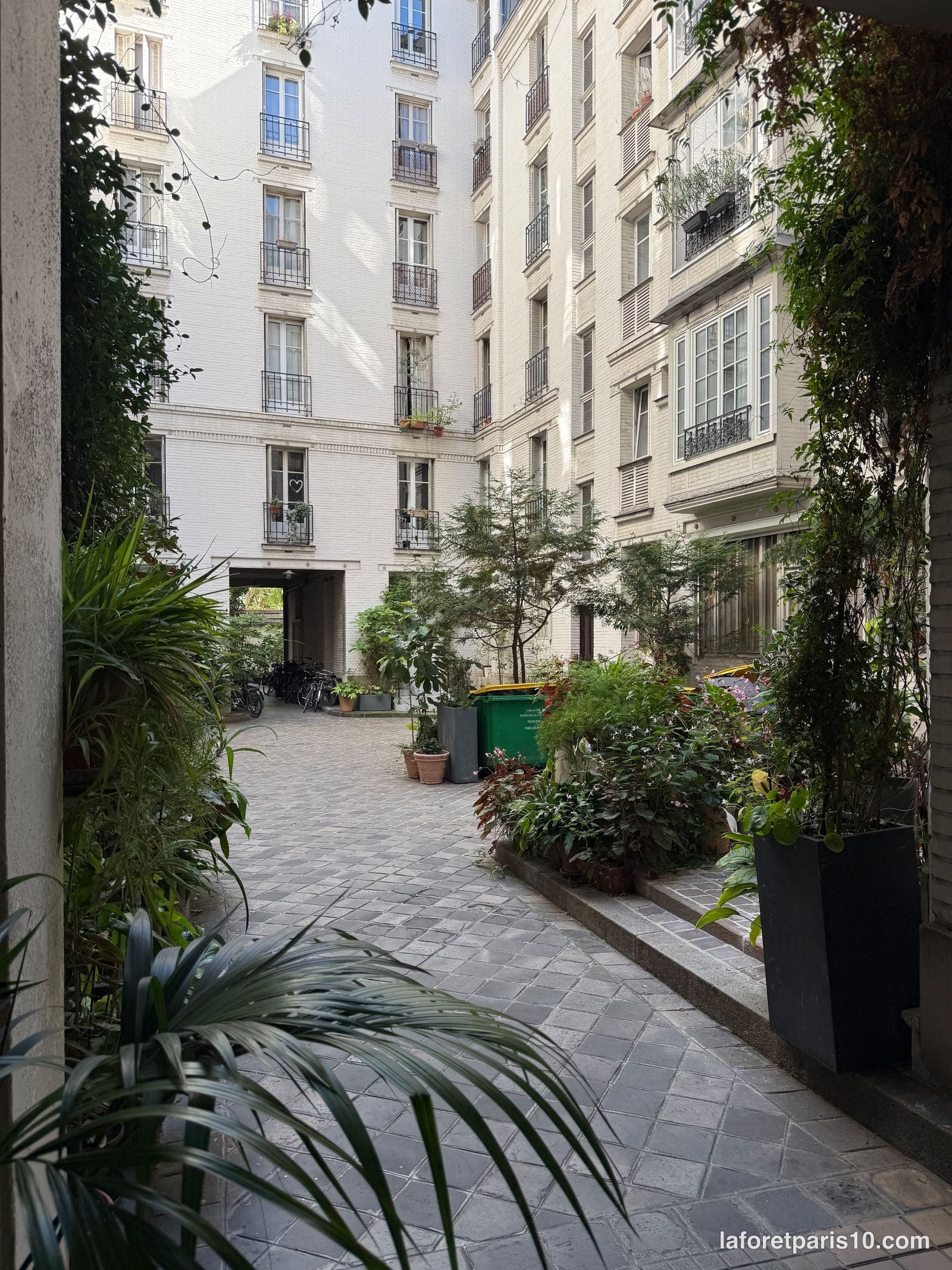 Cour pavée et plantée du 210 rue du Faubourg Saint-Denis, Paris 10e, bordée de façades en brique claire