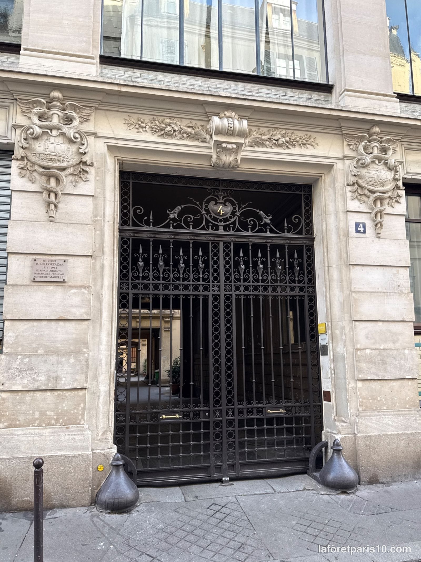 Porte cochère en grille de fer forgé entre deux cartouches sculptés, 4 rue Martel, Paris 10e