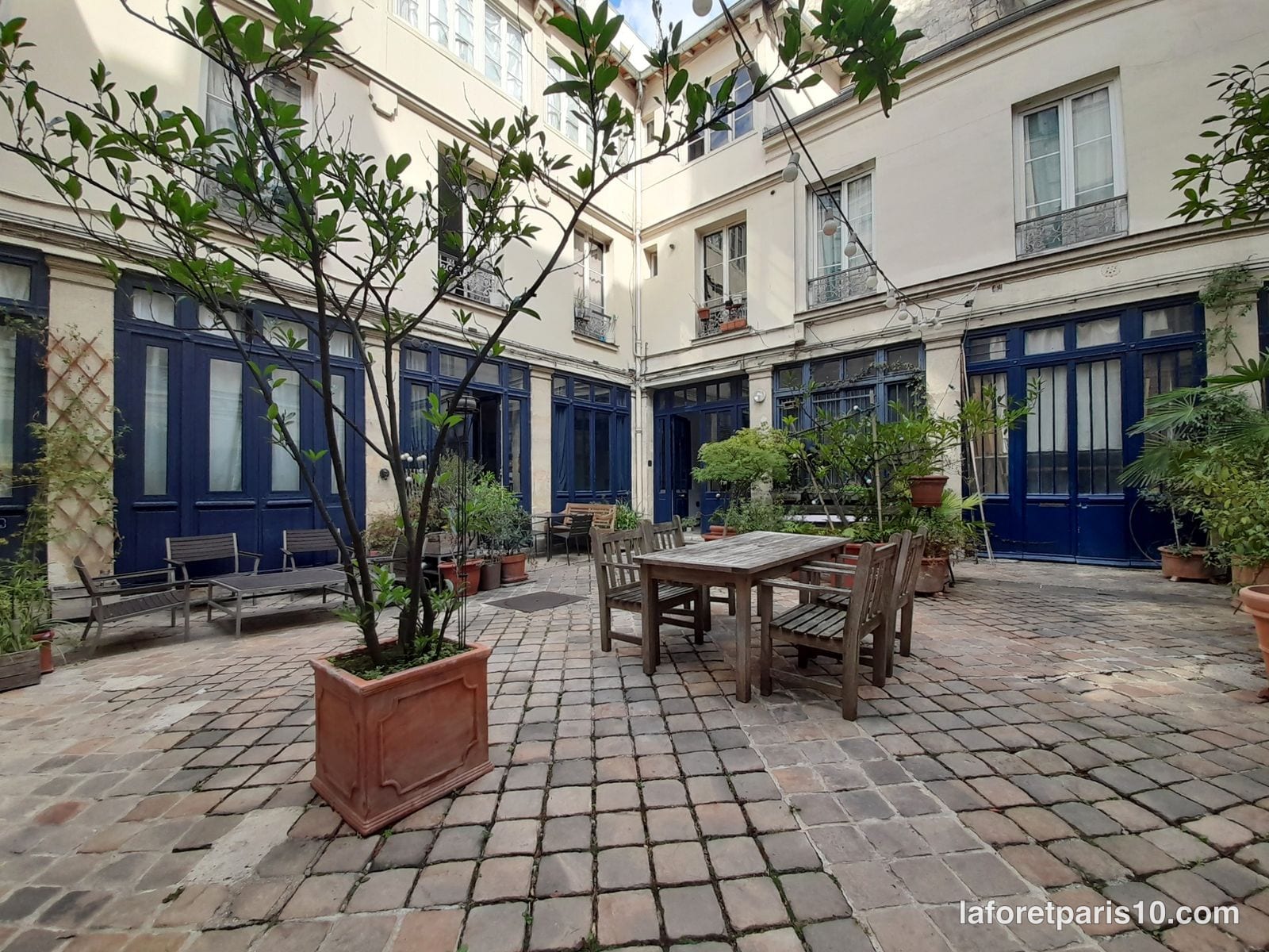 Cour pavée du 56 rue de Paradis, Paris 10e, bordée d'anciens ateliers aux menuiseries bleues